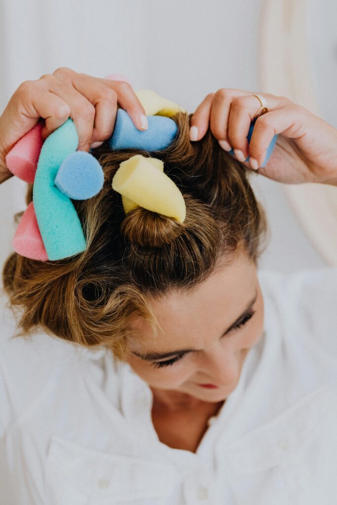 Close-up of a woman styling her hair using colorful curlers for a casual look.